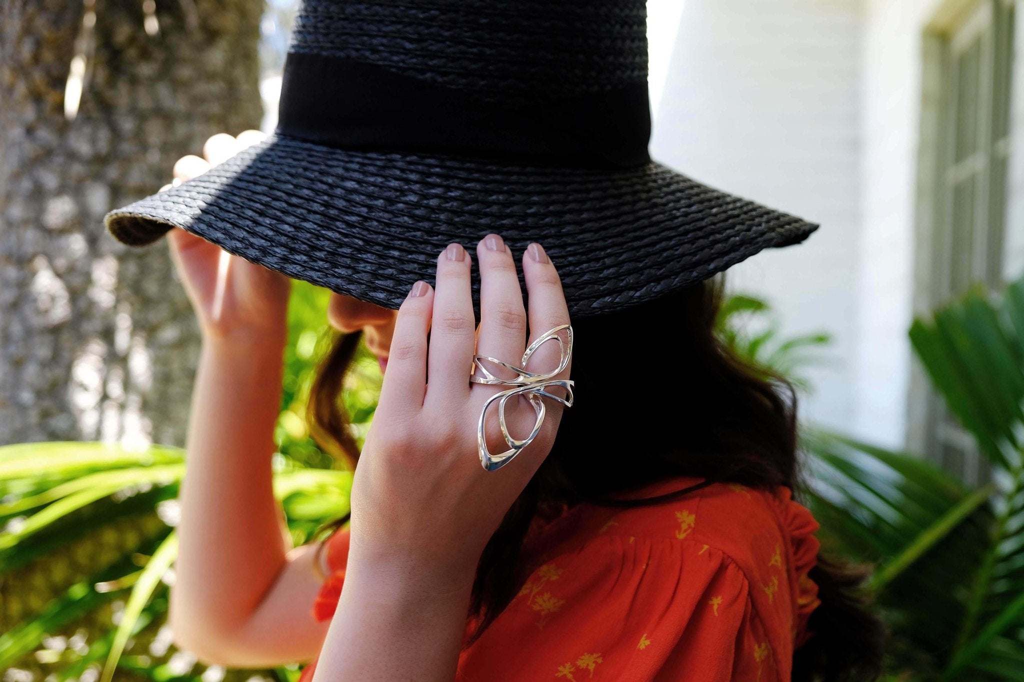 Woman wearing silver statement ring and black wide-brimmed hat in outdoor summer setting for End of Summer Pop-Up Sale
