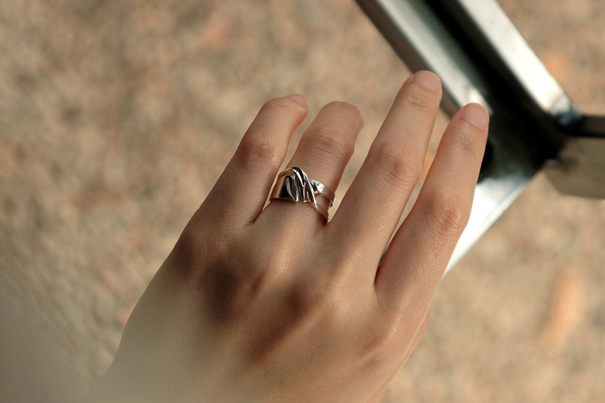Close-up of a hand wearing a silver Velum Ring with a drapery-inspired design on the finger