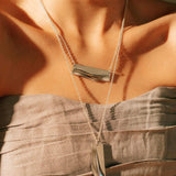Adagio stainless steel pendant necklace with twisting and stacking curves worn on a woman