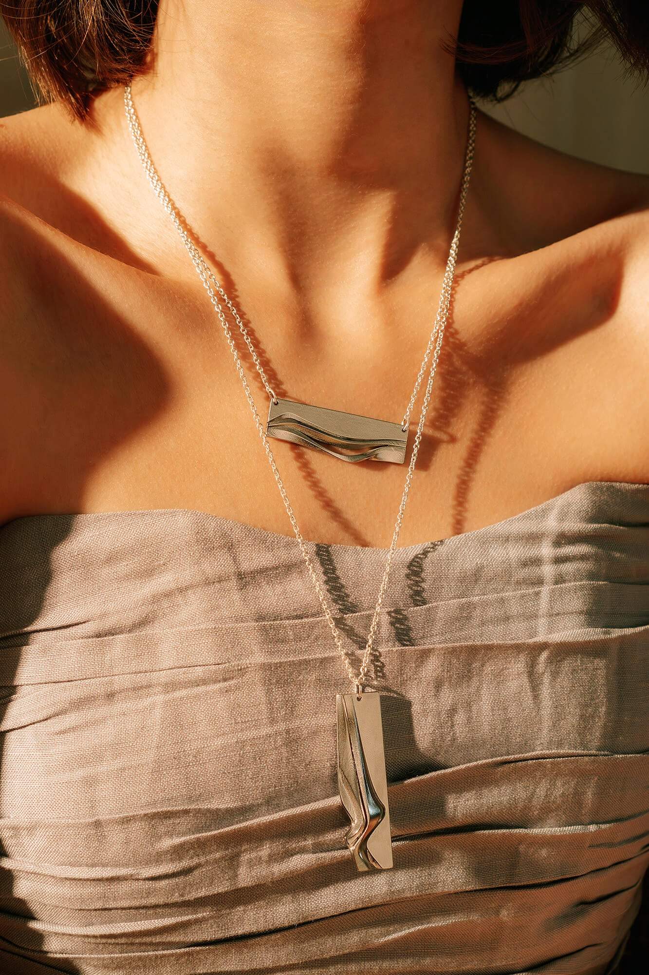 Adagio stainless steel pendant necklace with twisting and stacking curves worn on a woman