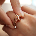 close-up of hand wearing rose gold Amare Sera Ring set with intertwined knot design