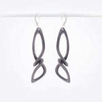 Centri Earrings in black steel with long, loose knot design and precision edge detailing