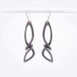 Centri Earrings in black steel with long, loose knot design and precision edge detailing