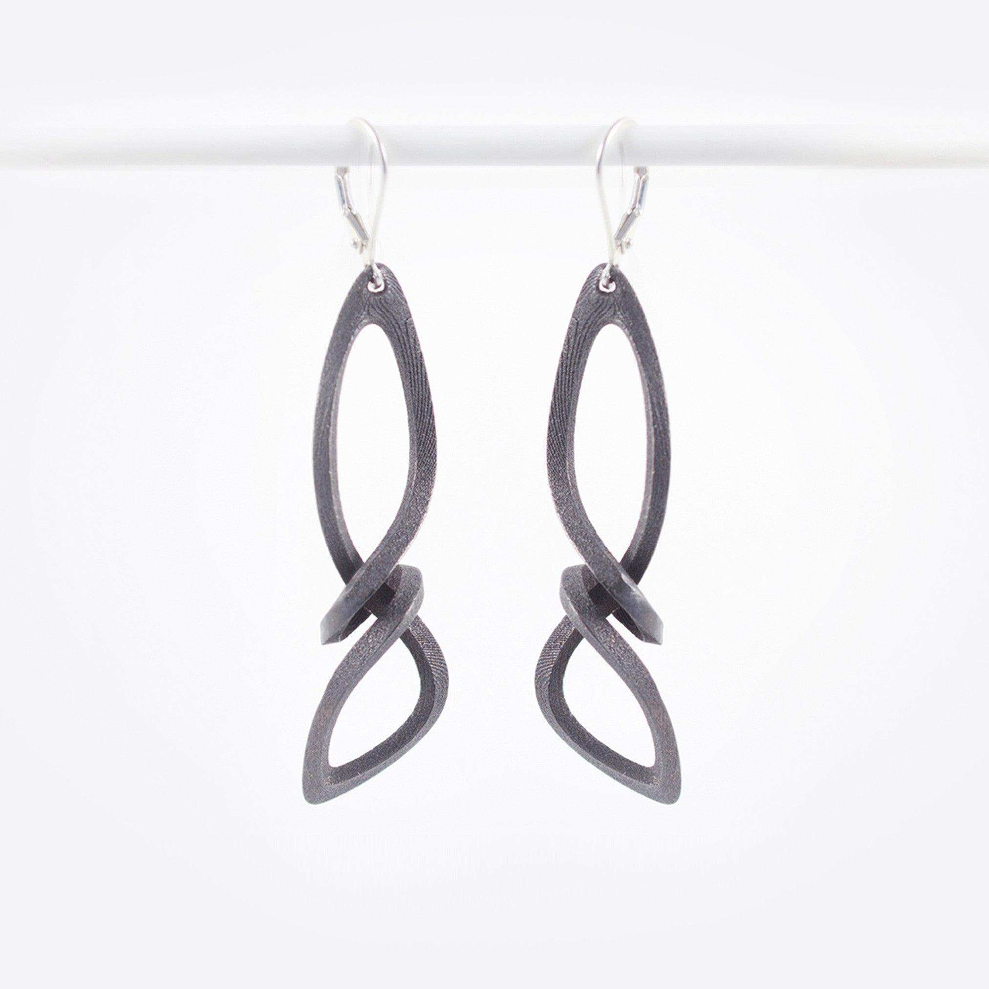 Centri Earrings in black steel with long, loose knot design and precision edge detailing