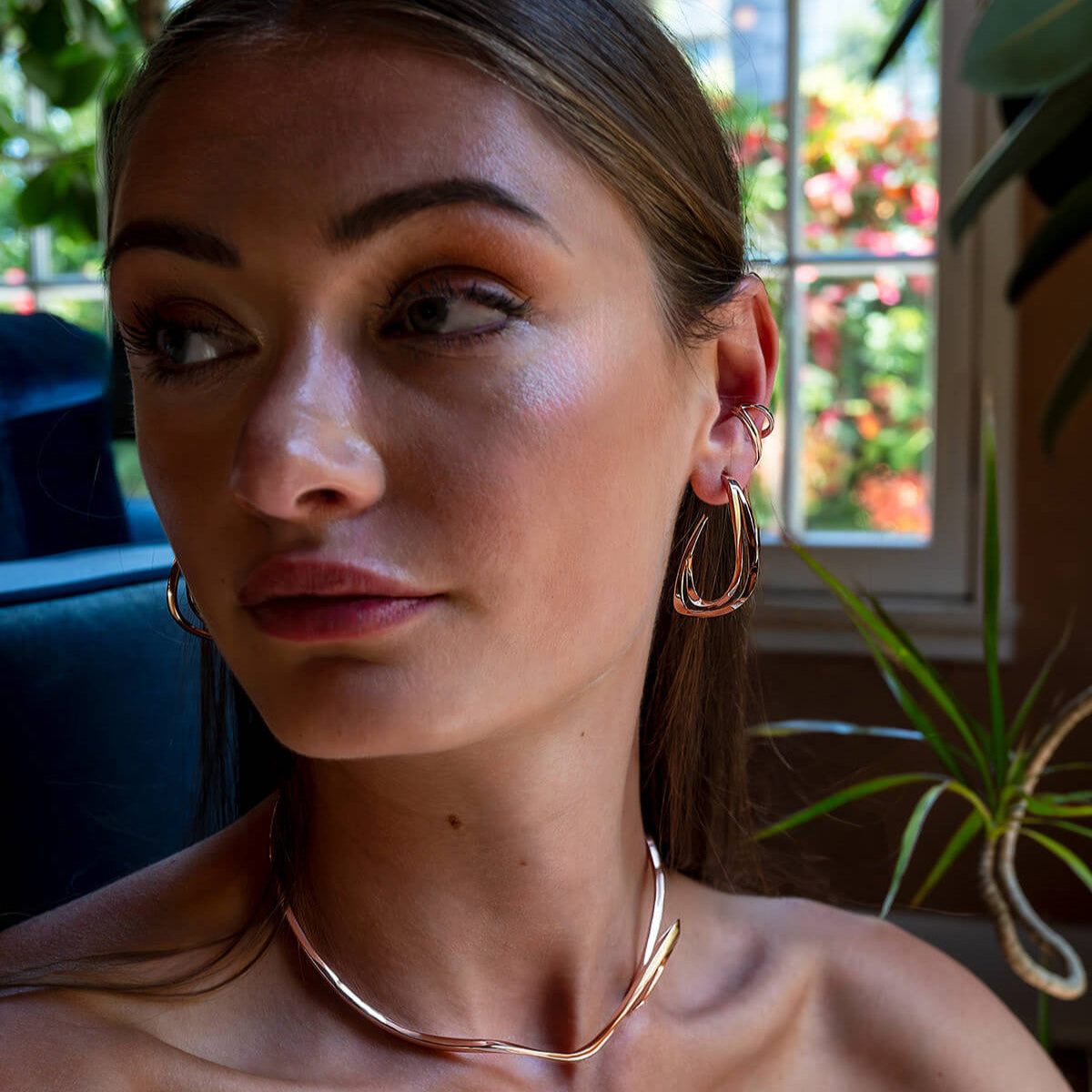 Woman wearing a sculptural Cascade Ear Cuff with flowing undulating curves in sterling silver, styled for elegant layered look