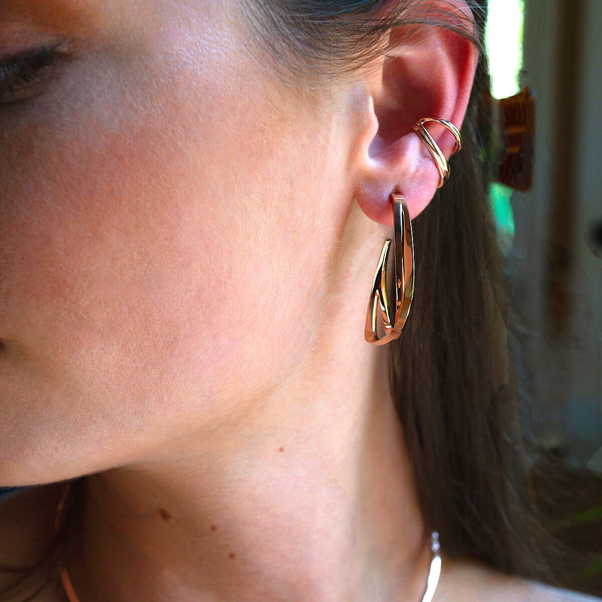 close-up of ear wearing gold Cascade Ear Cuff with twisted design along lower ear beside lobe