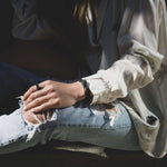 Person wearing sleek Allegro Cuff Carbon fiber bracelet with twisting, stacked curves and precision edges on wrist, styled with casual ripped jeans and white blouse