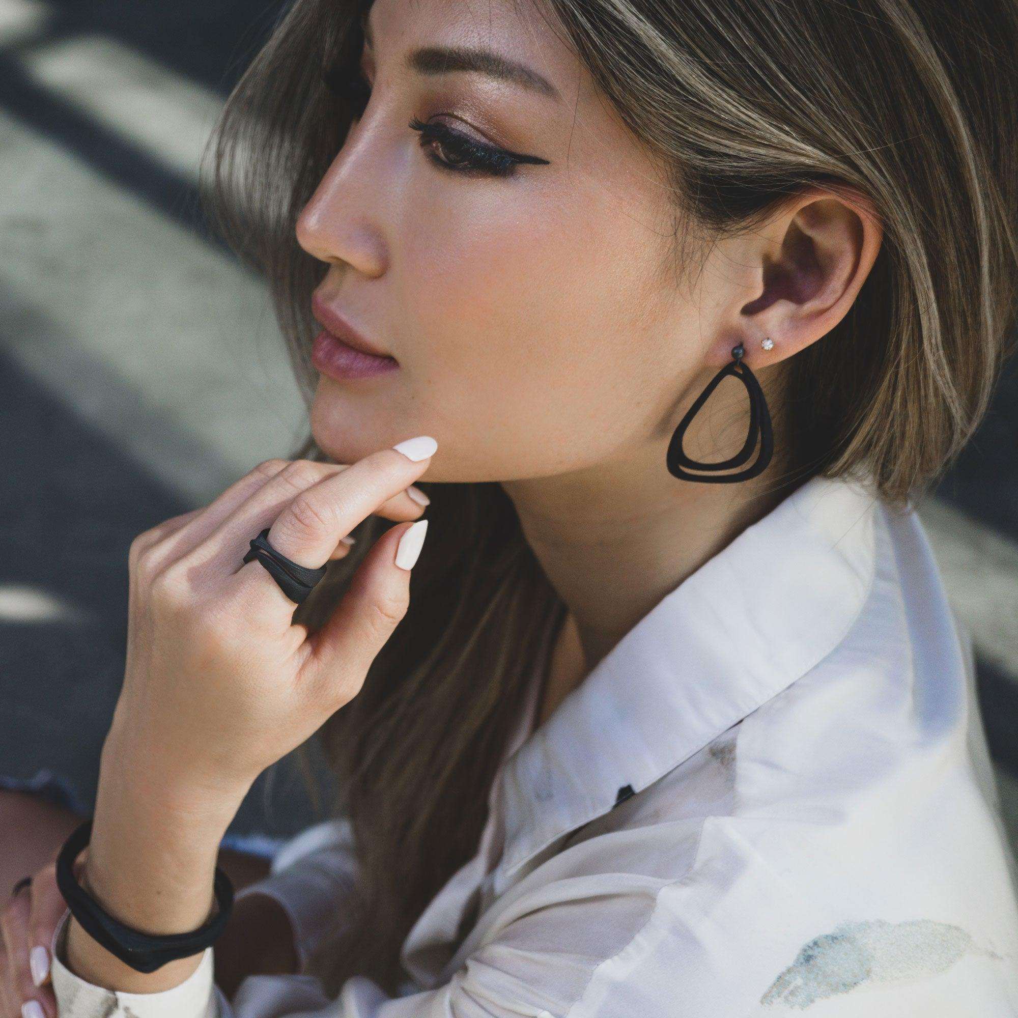 Woman wearing lightweight Aura Carbon black 3D printed carbon fiber earrings with misaligned loop design