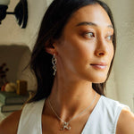 Woman wearing Nova earrings with a loose knot design in sterling silver