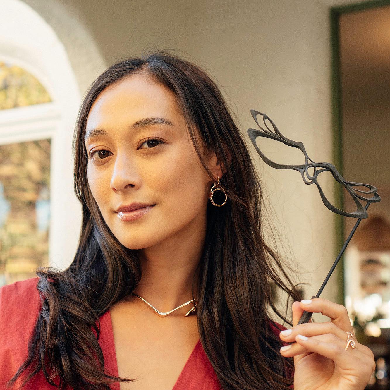 Woman holding LACE's exquisite 3D-printed nylon masquerade mask with intricate linework in gray nylon
