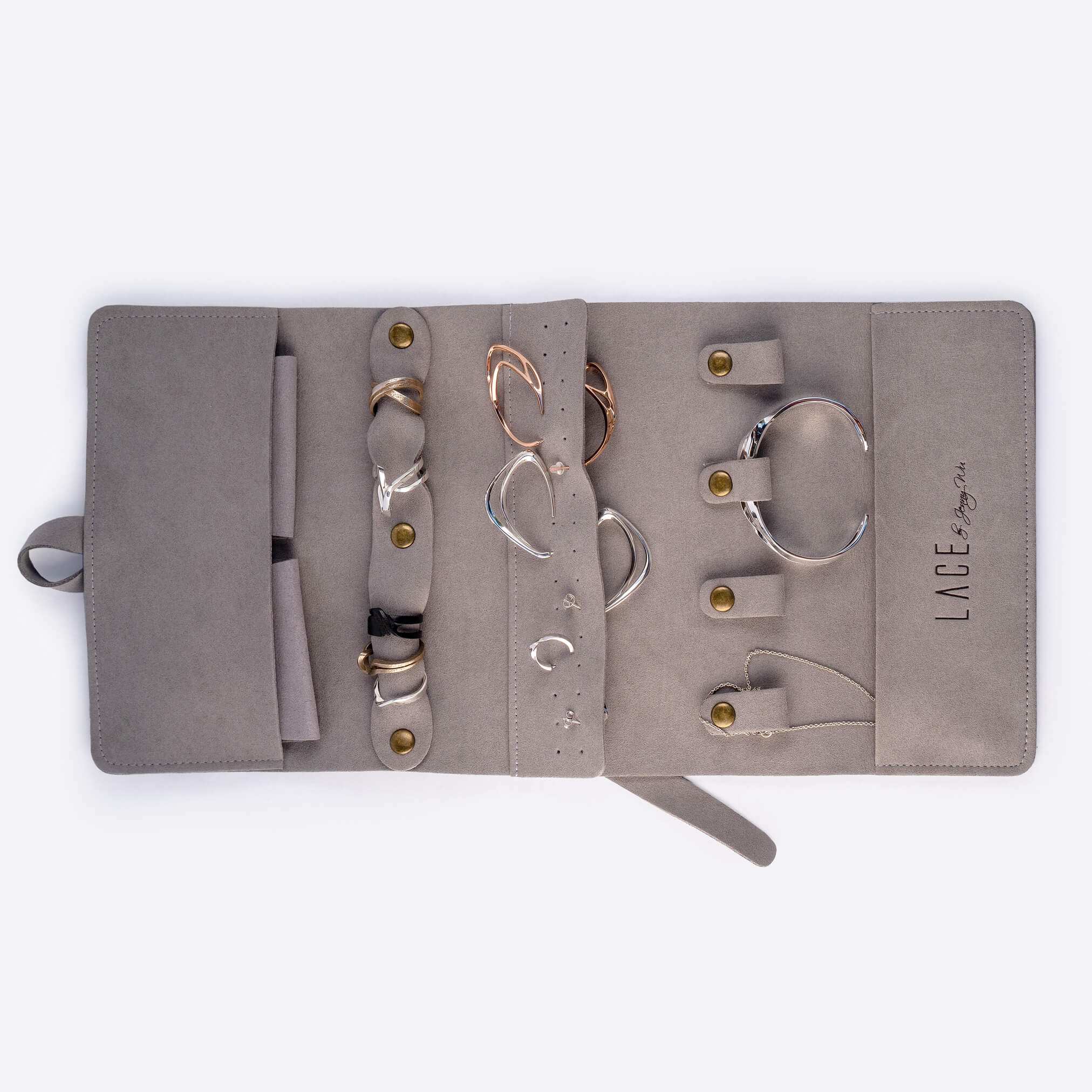 Gray travel jewelry roll organizer with compartments holding rings, earrings, bracelets, and small pouches.