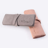 Travel jewelry roll organizer in gray and pink microfiber for rings, earrings, necklaces, and bracelets.