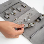 Gray travel jewelry roll organizer made of soft microfiber with compartments for rings, earrings, and bracelets.
