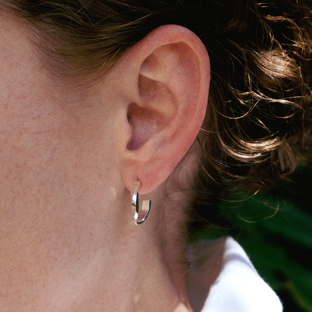 Close-up of a person wearing sterling silver Linea Earrings Set with a mini hoop earring on the earlobe.