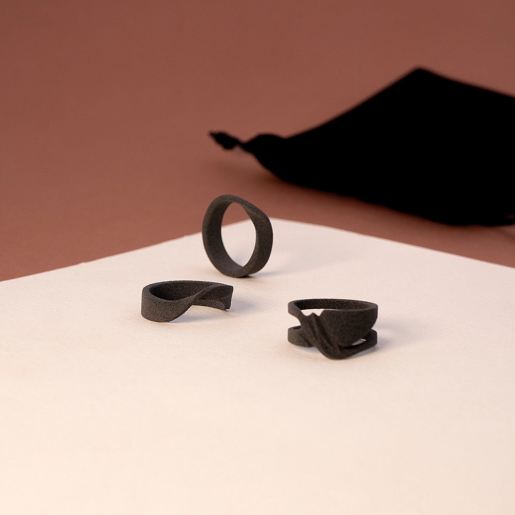 Men's ring samples set with three nylon ring designs on white and brown background with black velvet pouch