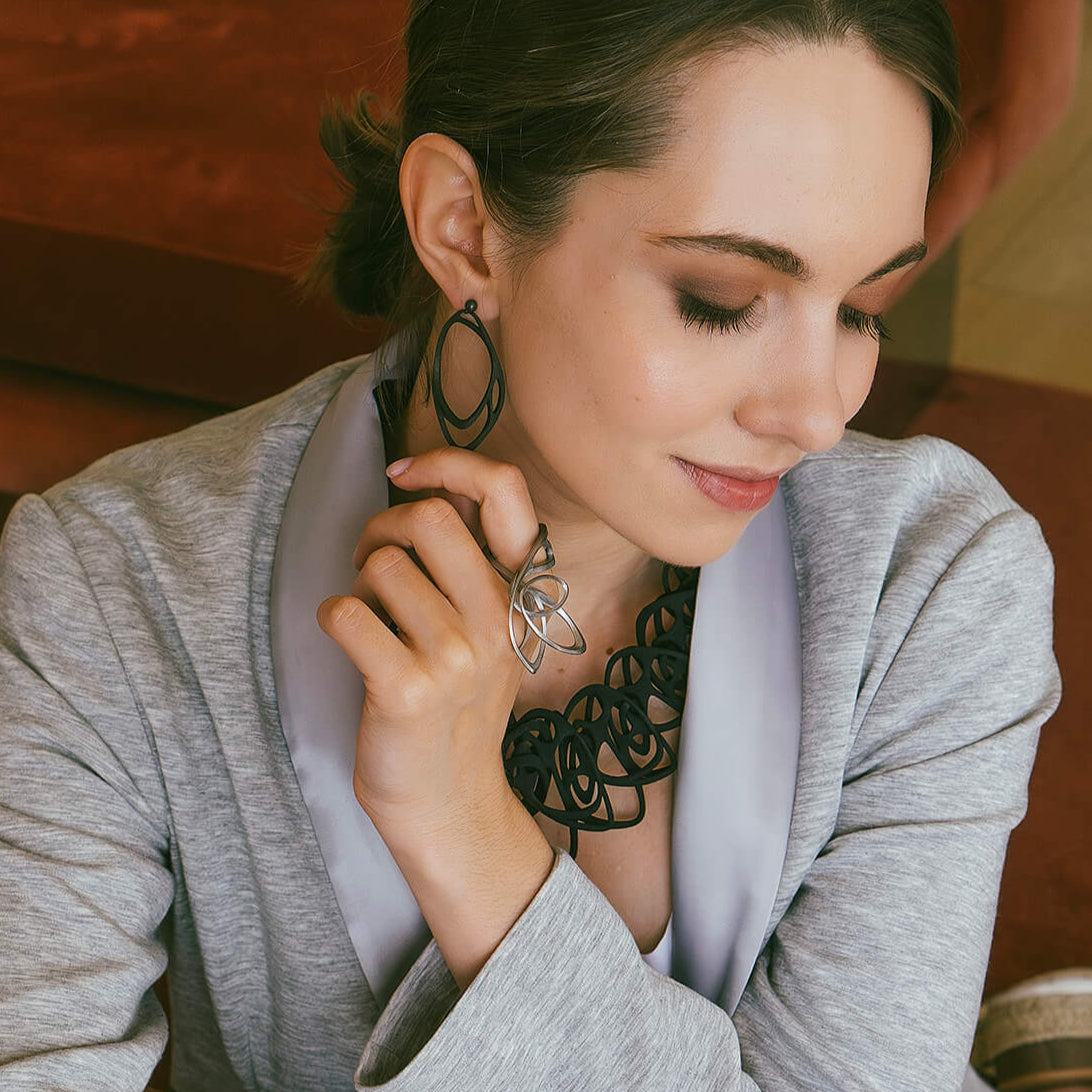 Woman wearing Eclipse Carbon Earrings with layered oval rings in carbon fiber and 3D printed design