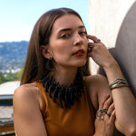Woman wearing lightweight black Aura Carbon fiber hoop earrings with two misaligned loops and precision edge detailing