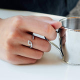 Hydra Stainless Steel Ring on finger holding silver cup with an open curved oval loop design