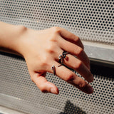 Hydra Stainless Steel Ring open curve design worn on finger with metal mesh background