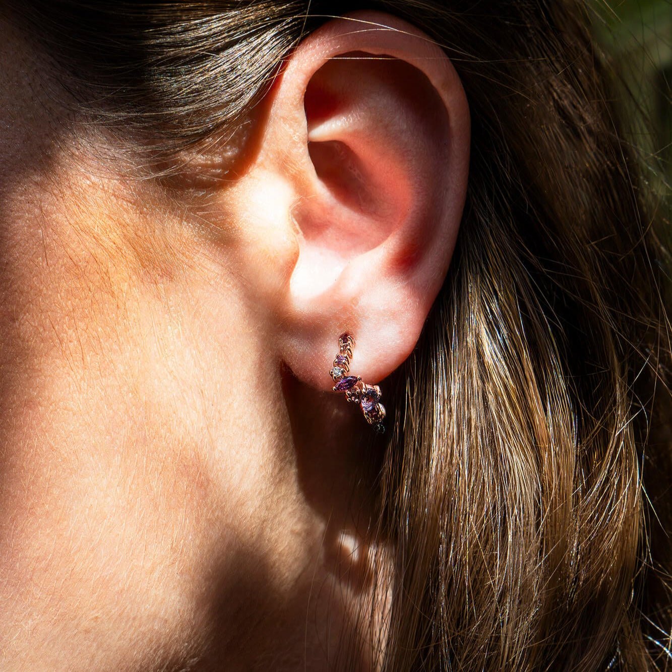 Close-up of ear wearing Leda Earrings with amethyst, rhodolite, pink tourmaline, and white topaz gemstones in 18K rose gold vermeil hoops