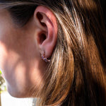 Close-up of ear wearing Leda Earrings gemstone hoops in 18K rose gold vermeil with lilac and pink stones