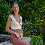 Woman wearing Leda gemstone necklace in garden setting with green foliage background