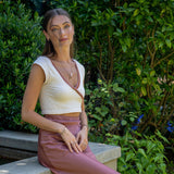 Woman wearing Leda gemstone necklace in garden setting with green foliage background