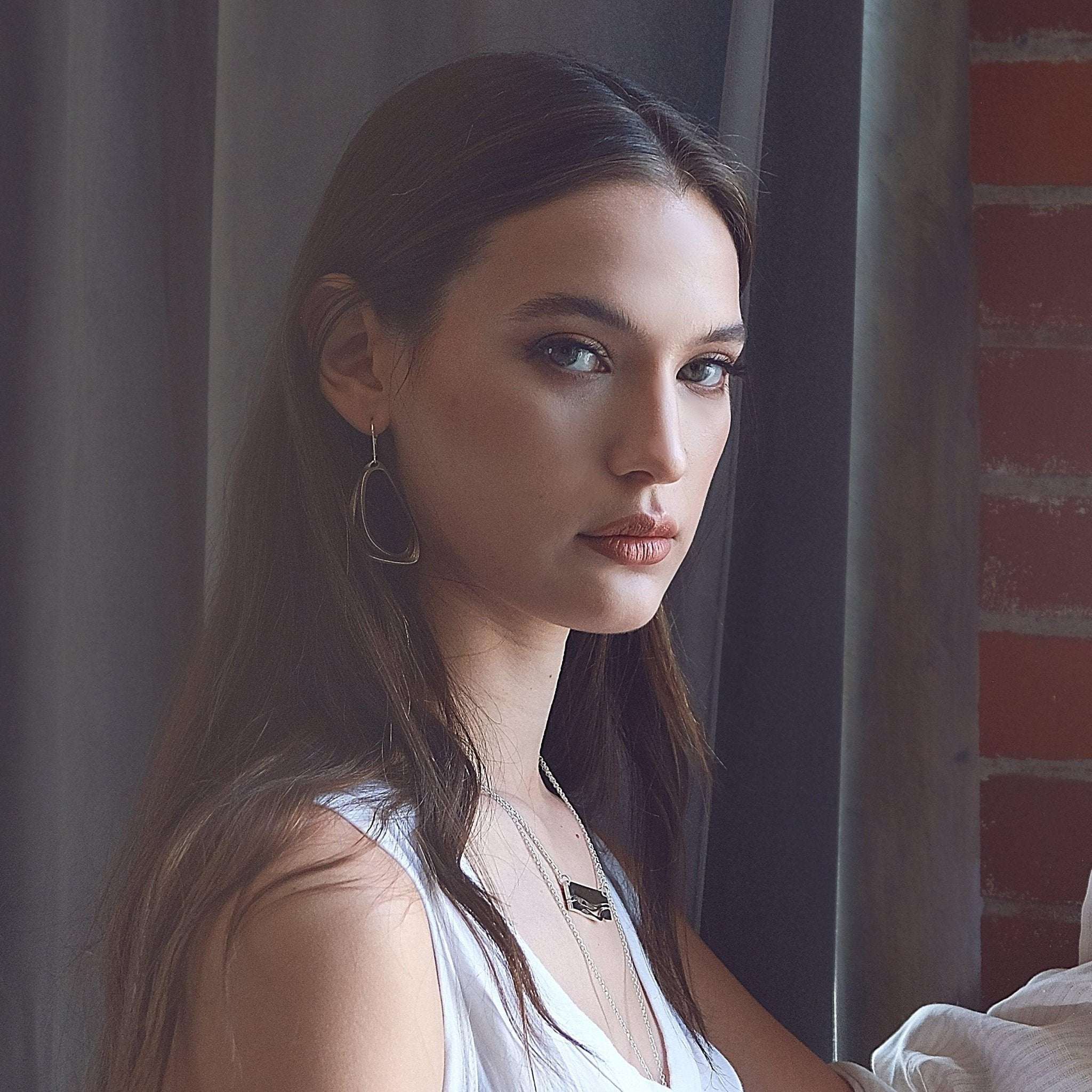 Woman wearing Aura Steel stainless steel earrings with two angled loops and precision edge detailing