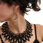 Woman wearing Aura Steel stainless steel misaligned loop earrings and black necklace