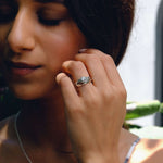 Close-up of woman wearing Iris Diamond Ring with round center diamond and detailed band design