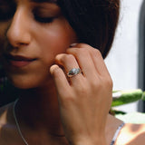 Close-up of woman wearing Iris Diamond Ring with round center diamond and detailed band design