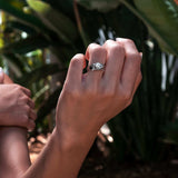 Close-up of hand wearing Iris Diamond Ring with 0.5 carat round diamond and intricate drapery design outdoors
