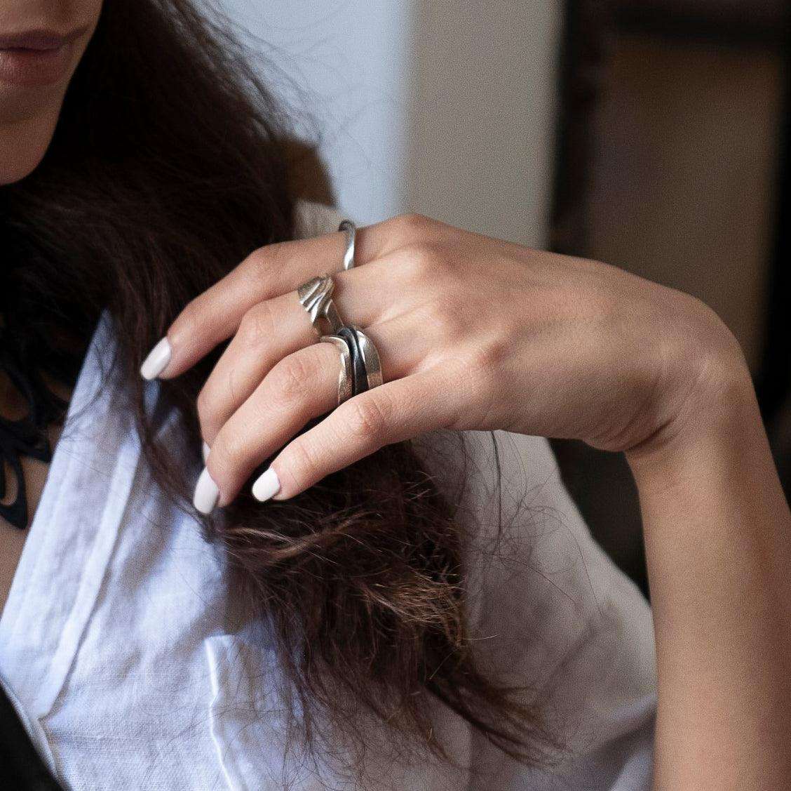 Close-up of hand wearing Amor Stainless Steel Ring with a twisting band and precision edge detailing