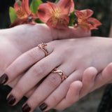 Amor Amos Light Set with stackable rose gold rings on hands with flowers background
