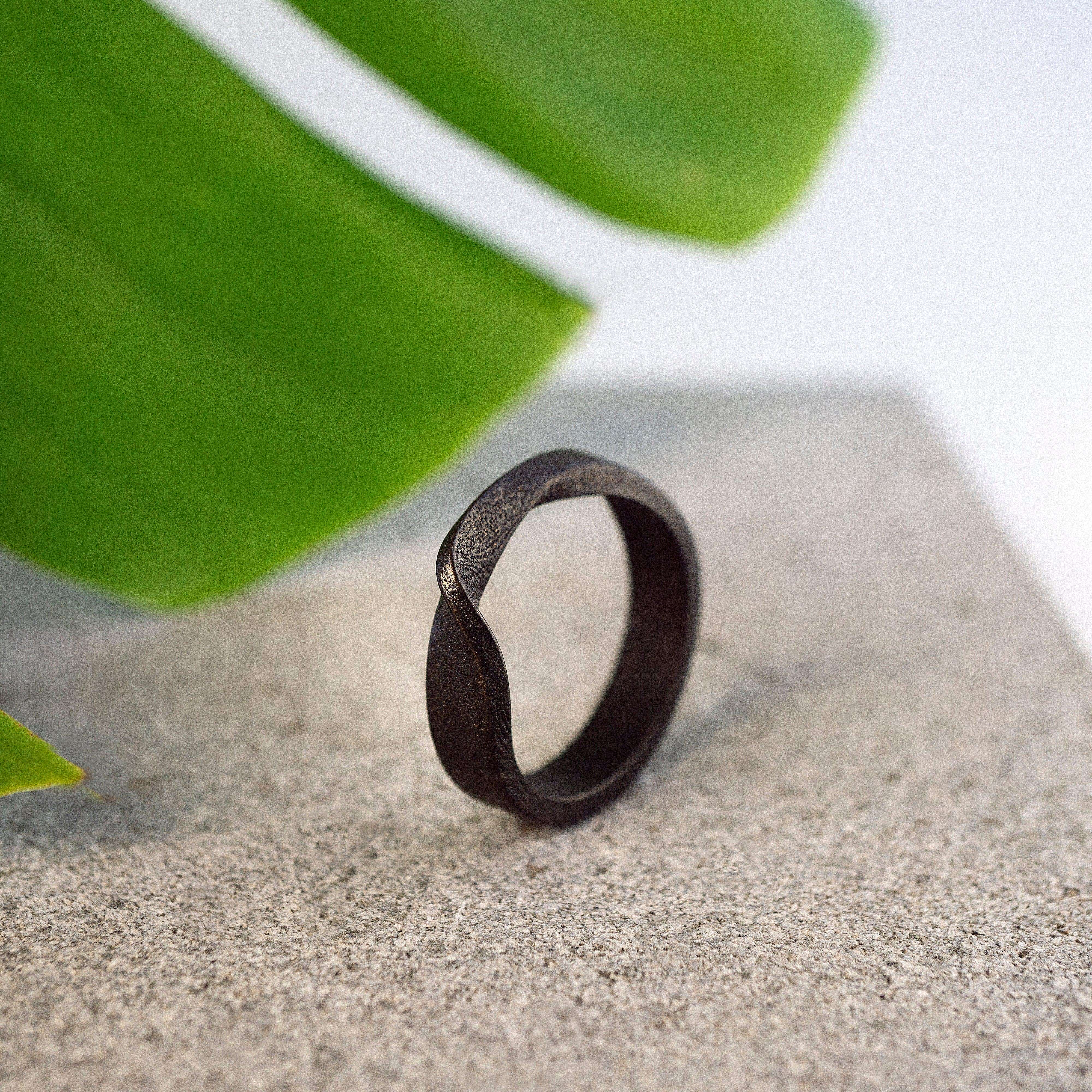 Amor Bold Steel Ring in gray steel with twisted band and precision edge details on stone surface