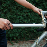 Man wearing Amor Bold Steel Ring on hand while holding a silver bicycle frame outdoors