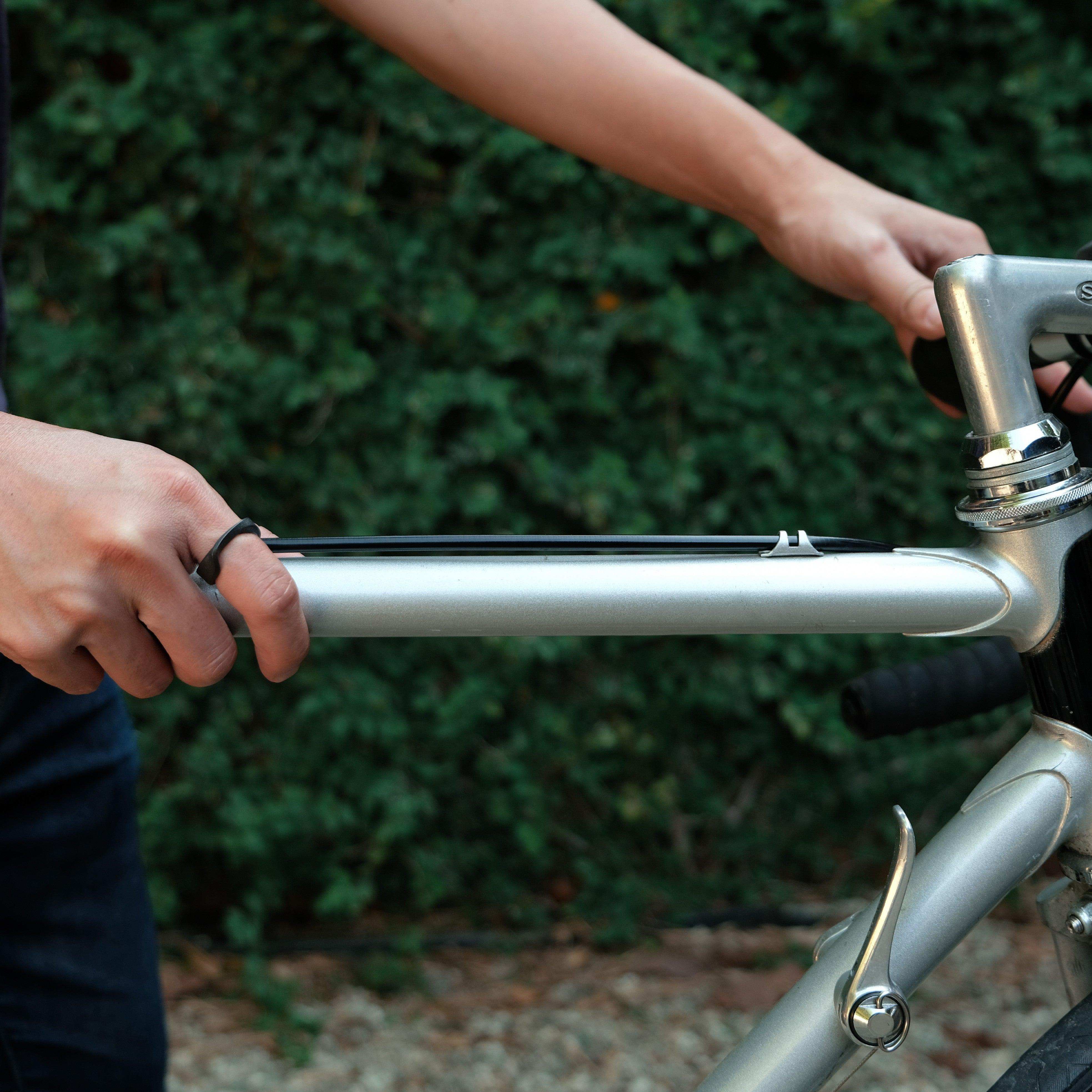 Man wearing Amor Bold Steel Ring on hand while holding a silver bicycle frame outdoors