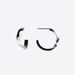 Close-up of silver Linea Mini Hoop earrings with open twisting band design on white background