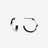Close-up of silver Linea Mini Hoop earrings with open twisting band design on white background