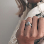 Close-up of a woman's hand wearing an elegant Lyra wedding ring with a large center diamond and detailed band, styled with minimal and clean design for women