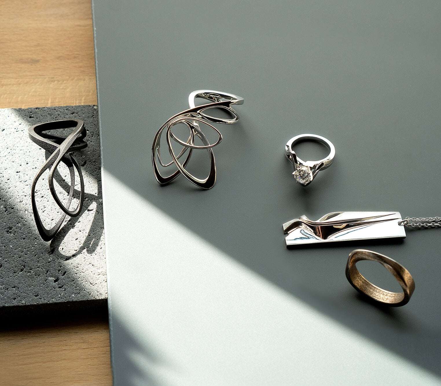 LACE jewelry design 3D printed elegant rings and necklace collection on gray surface with sunlight shadow