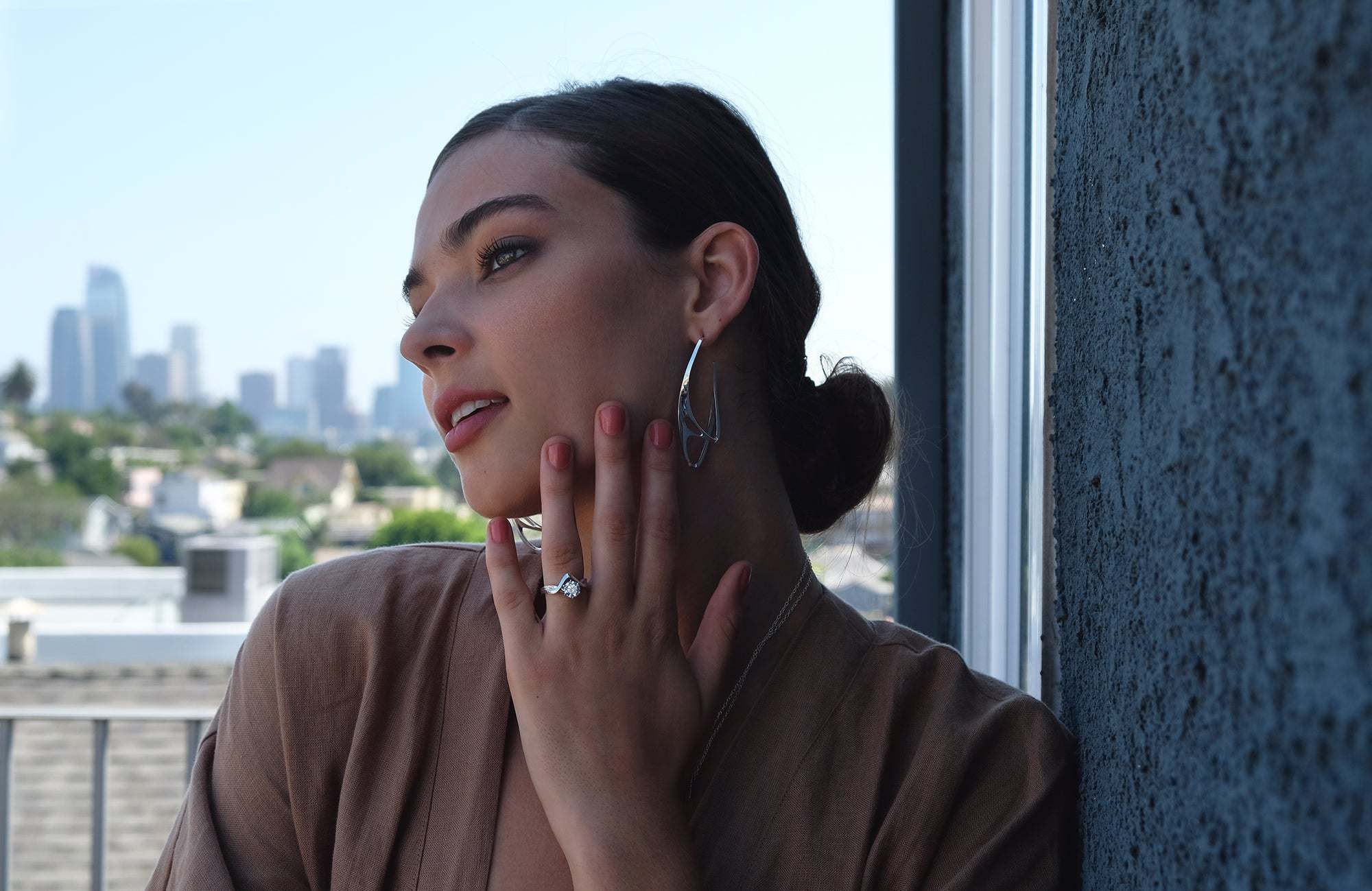 Elegant woman wearing statement ring and hoop earrings at Hong Kong Launch jewelry event