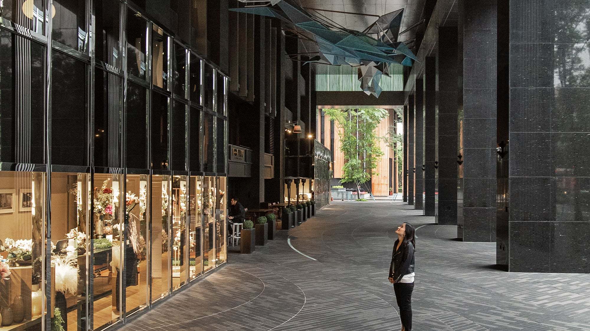 woman standing in modern urban walkway with tall black pillars reflecting cityscape at end of year 2023 reflection session