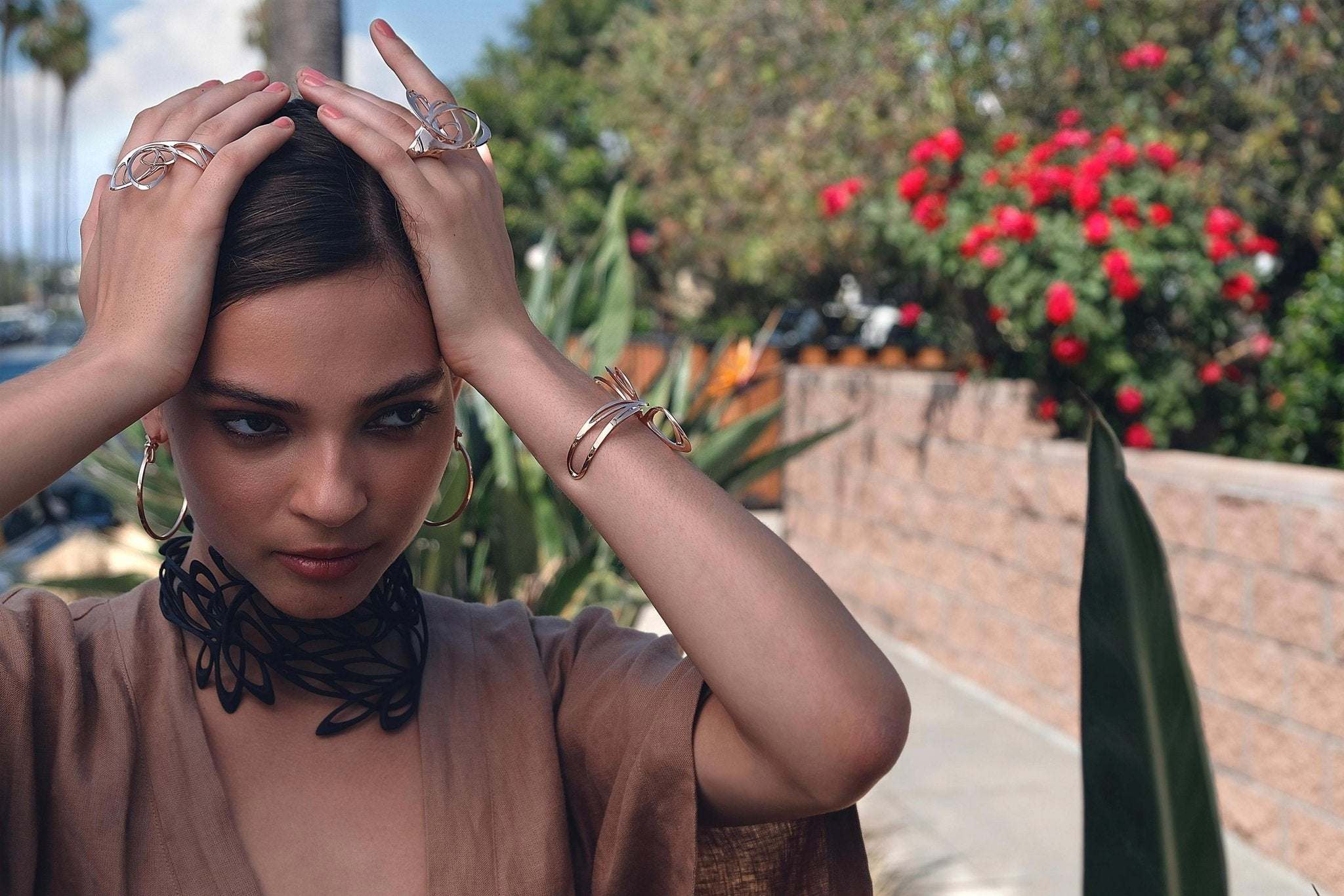 Woman wearing summer accessories including rings, bracelets, and hoop earrings in outdoor setting summer style guide