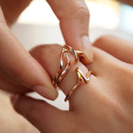 Close-up of two rose gold Eternal Knot Ensemble rings symbolizing love and unity on fingers