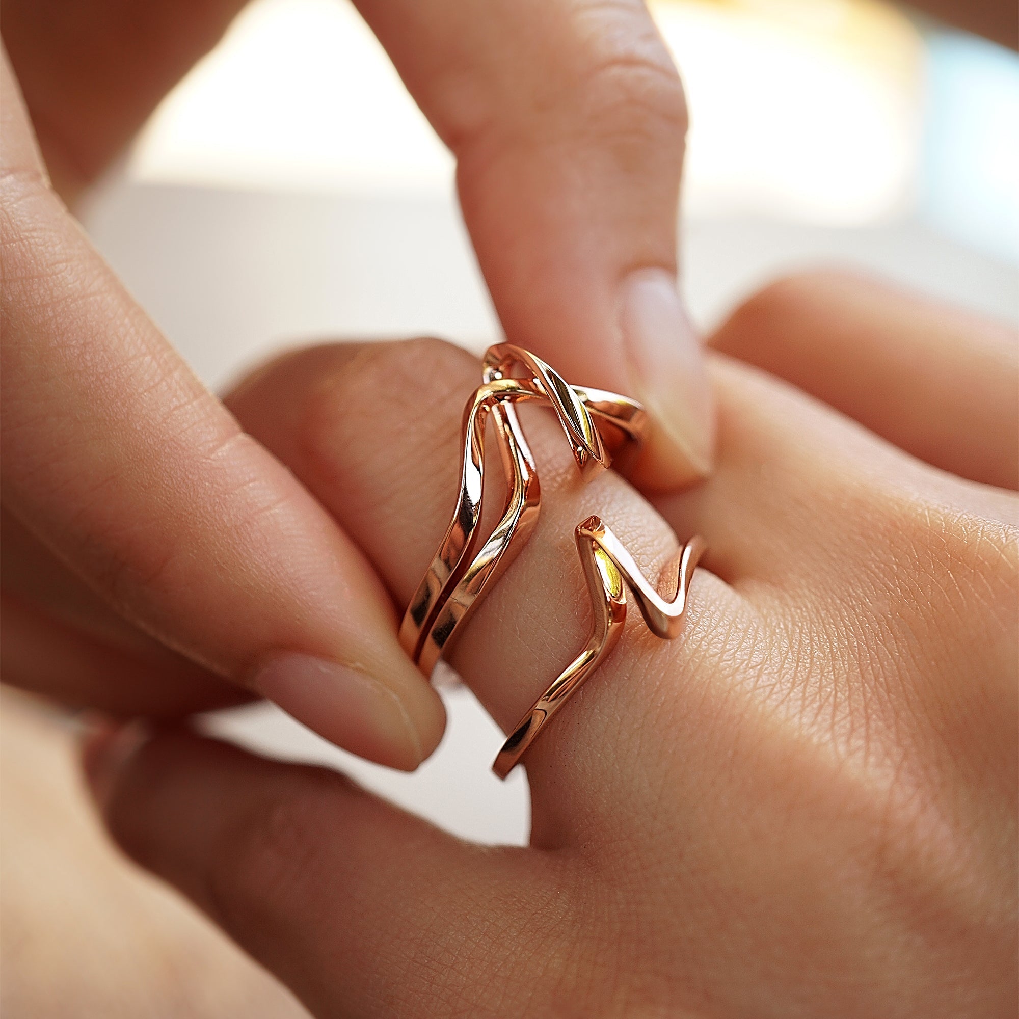 Close-up of two rose gold Eternal Knot Ensemble rings symbolizing love and unity on fingers