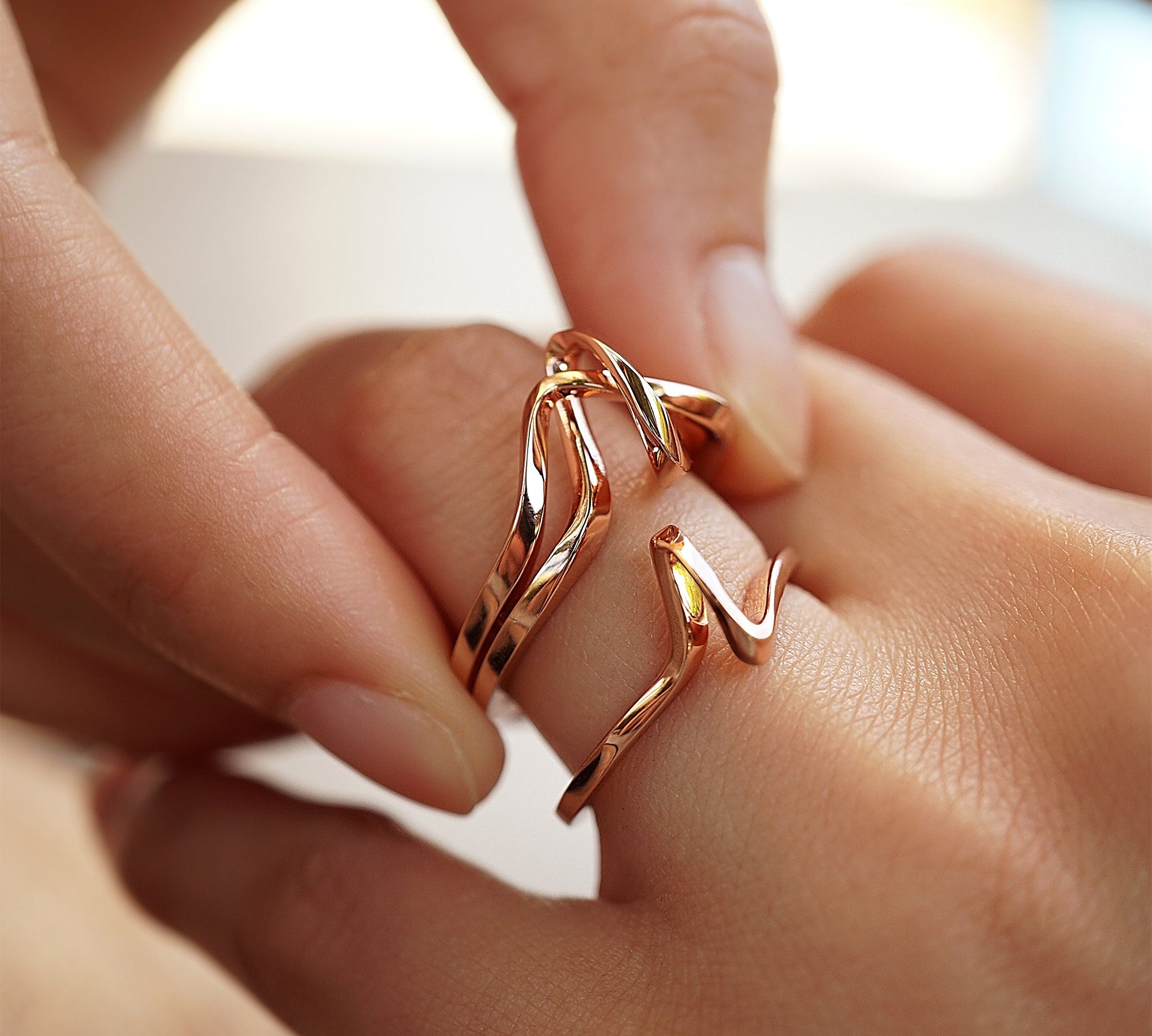 Close-up of hand wearing intertwined Amare Sera Ring set in 18K rose gold vermeil
