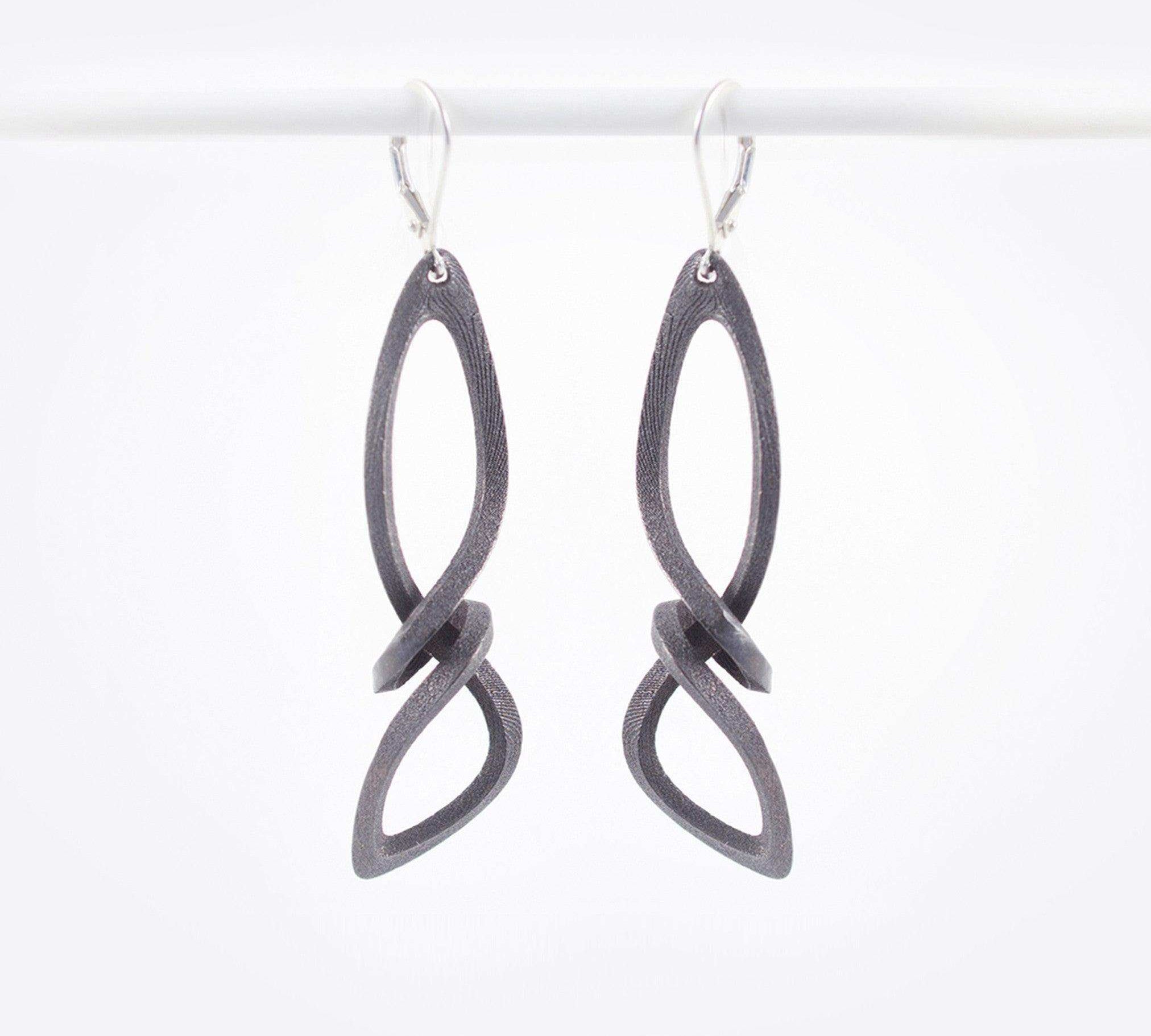 Centri Earrings in black steel with long, loose knot design and precision edge detailing