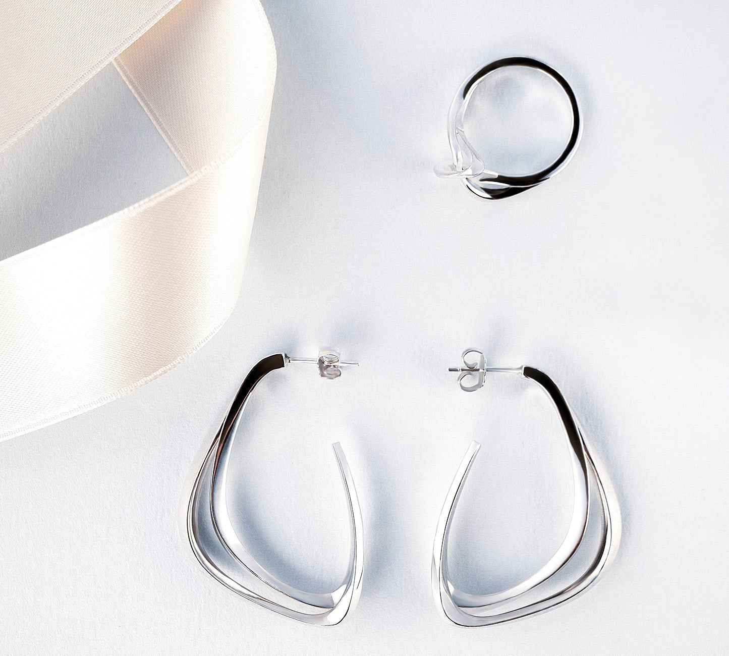 Silver Amare Aura Set featuring twisted ring and misaligned loop earrings with jewelry cleaning foam gift
