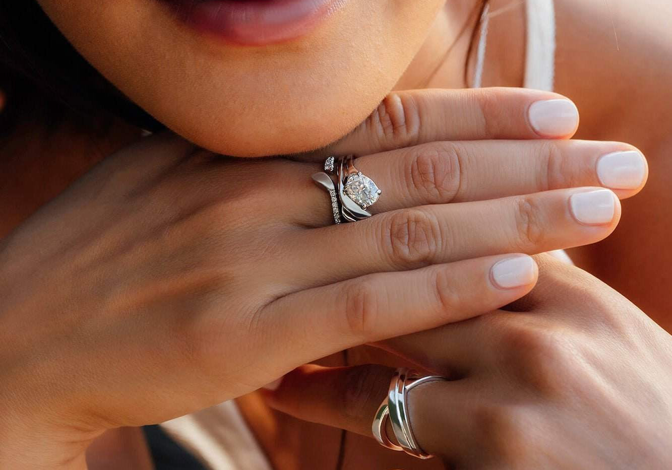 Close-up of a woman wearing a sculpted Rosae Wedding Band alongside a Calyx Engagement Ring on her finger